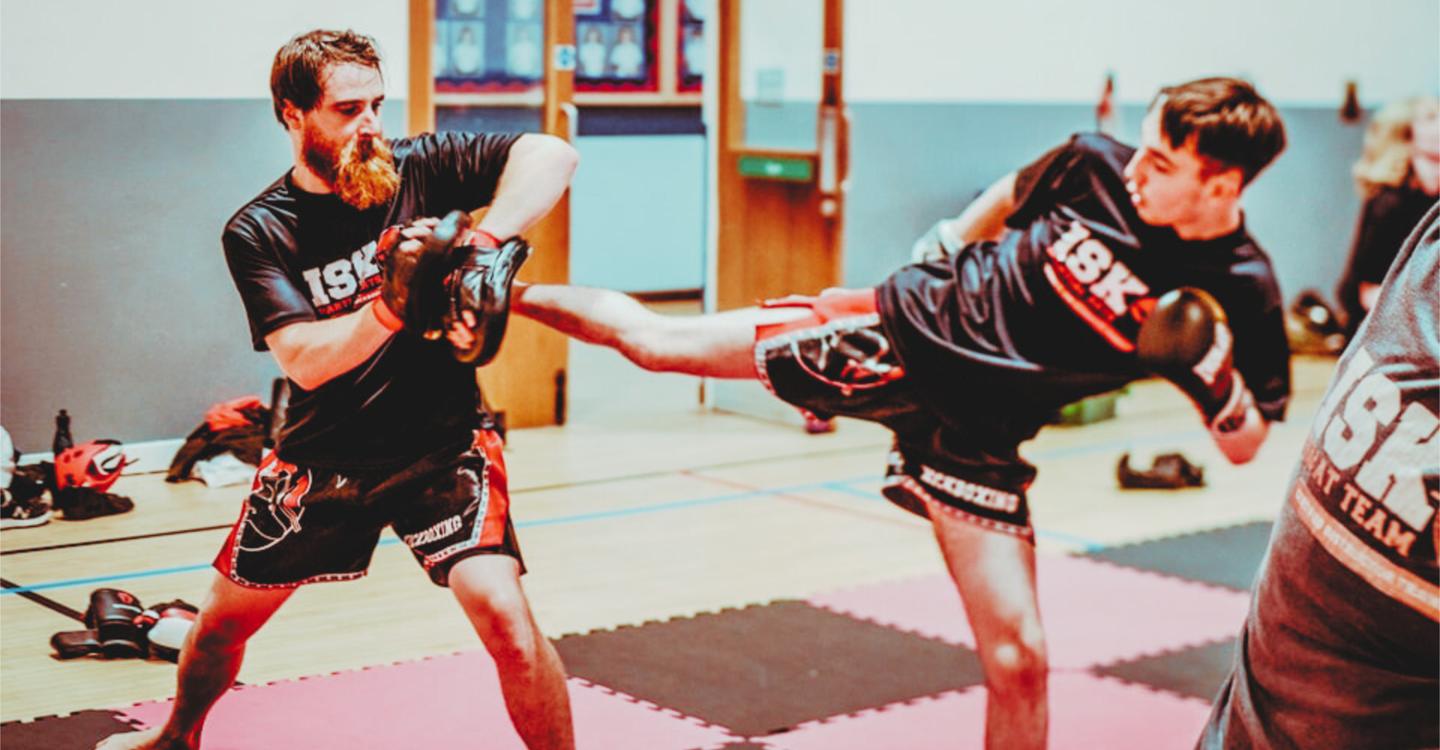Adults sparring with pads at an ISK Martial Arts kickboxing class in Redruth