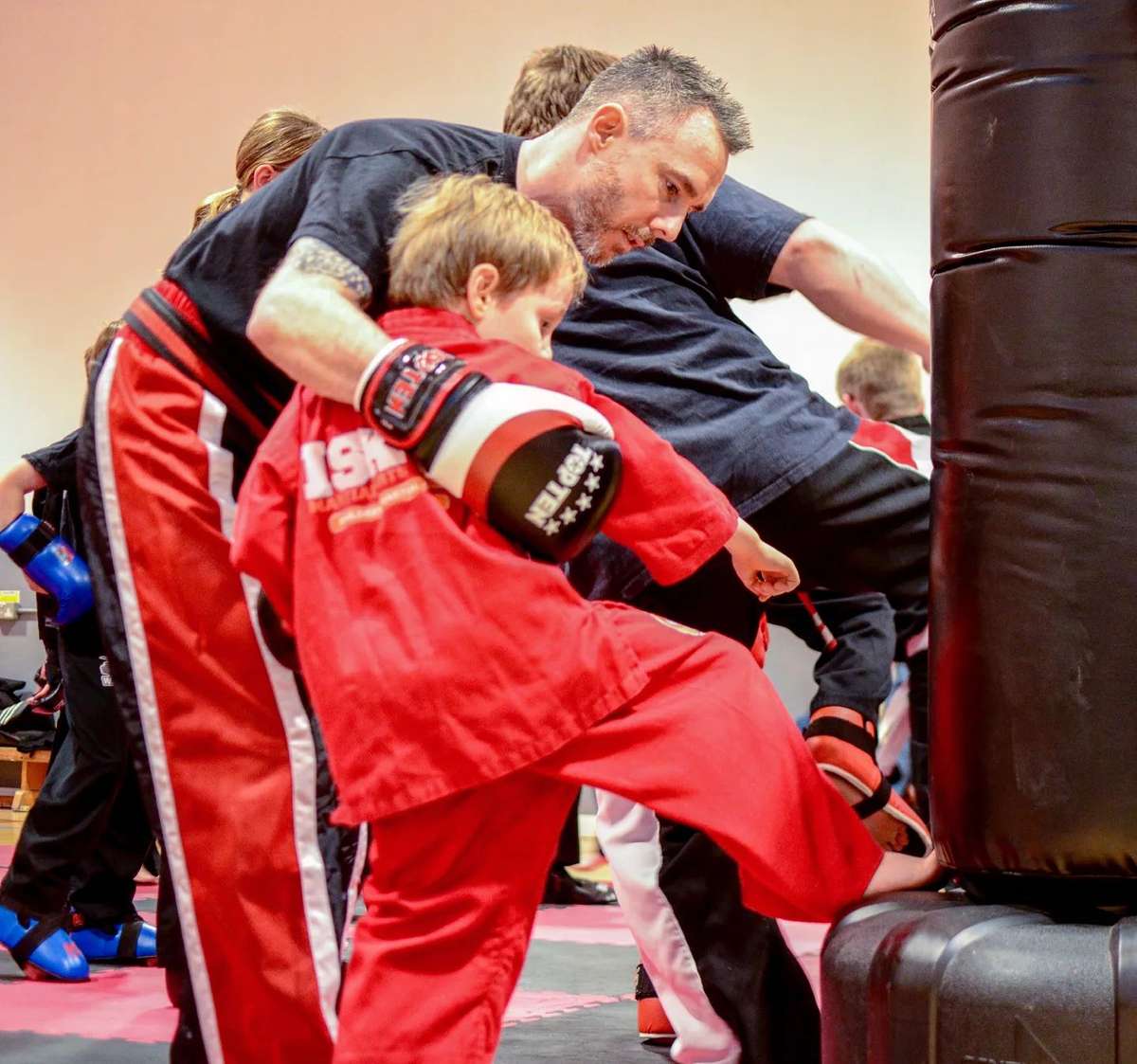An ISK Martial Arts instructor holding a bag for a young student in a Tiny Tigers class